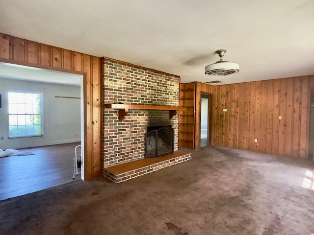 unfurnished living room featuring wooden walls, a fireplace, and dark hardwood / wood-style flooring