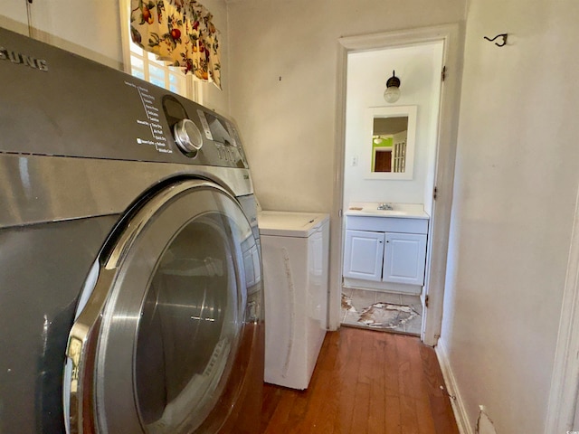 laundry room featuring washer and dryer, sink, and dark hardwood / wood-style flooring