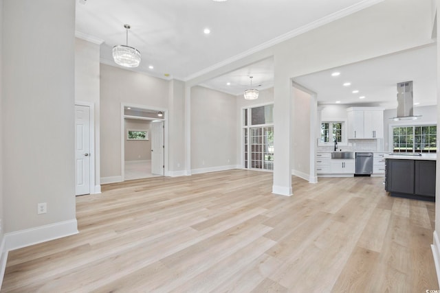 unfurnished living room featuring ornamental molding, a chandelier, light hardwood / wood-style flooring, and sink