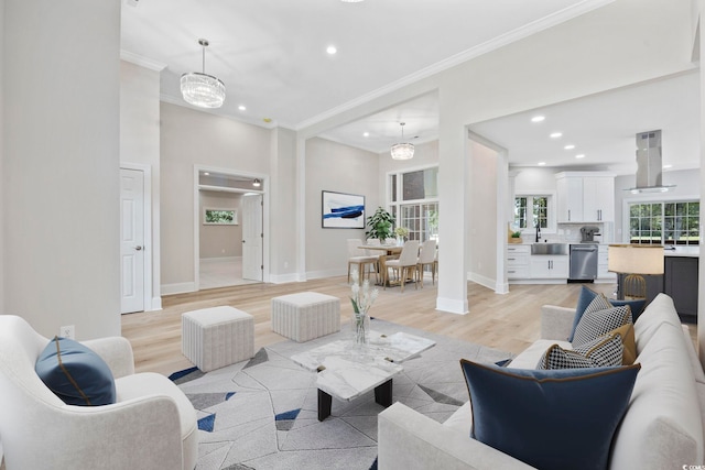 living room featuring sink, light hardwood / wood-style flooring, crown molding, and an inviting chandelier