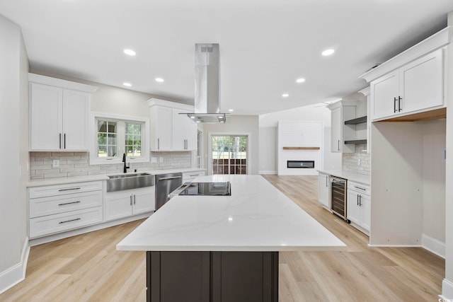 kitchen with light hardwood / wood-style flooring, island exhaust hood, white cabinets, and sink