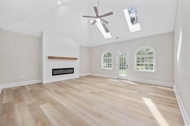 unfurnished living room featuring a large fireplace, light hardwood / wood-style flooring, high vaulted ceiling, and ceiling fan