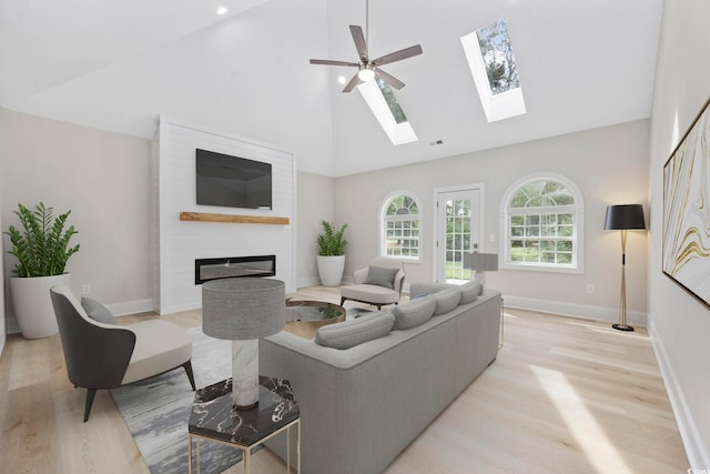 living room featuring light hardwood / wood-style flooring, a fireplace, high vaulted ceiling, and ceiling fan