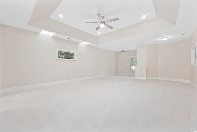 unfurnished room featuring ceiling fan, a tray ceiling, and light colored carpet