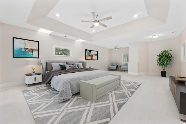 carpeted bedroom featuring ceiling fan, a raised ceiling, and multiple windows