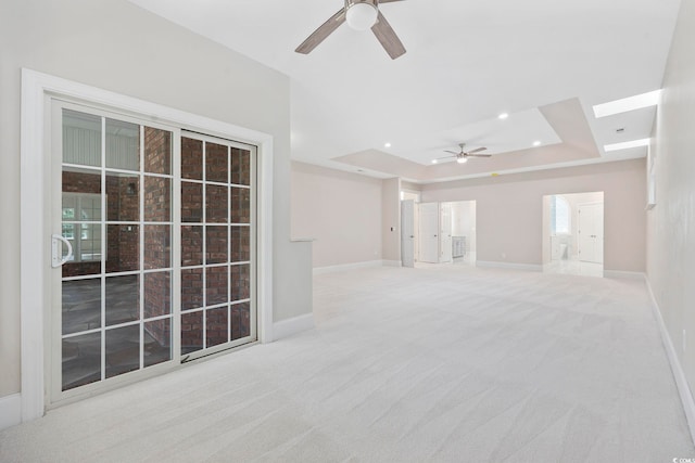 carpeted empty room featuring ceiling fan and a raised ceiling