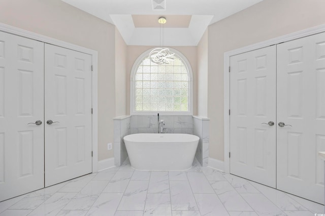 bathroom featuring tile walls, a notable chandelier, and a tub