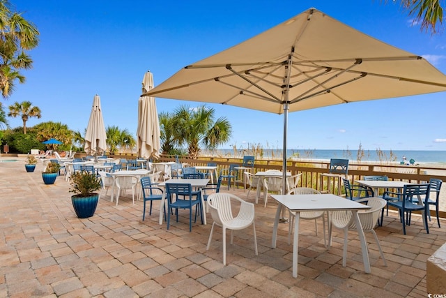 view of patio / terrace featuring a water view and a beach view