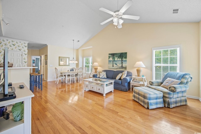 living room featuring ceiling fan, high vaulted ceiling, and light hardwood / wood-style floors