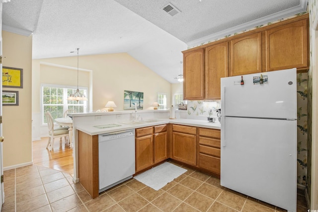 kitchen with lofted ceiling, sink, decorative light fixtures, kitchen peninsula, and white appliances