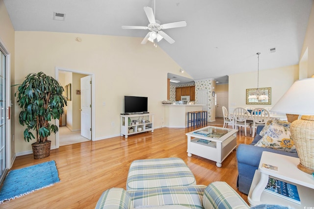 living room featuring high vaulted ceiling, ceiling fan with notable chandelier, and light hardwood / wood-style floors