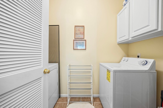 laundry room featuring cabinets, light tile patterned floors, and washer and dryer