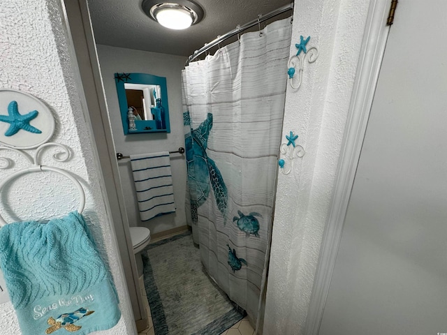 bathroom featuring toilet, a textured ceiling, and a shower with shower curtain