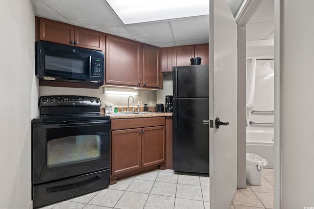 kitchen with black appliances, light tile patterned flooring, sink, and a drop ceiling