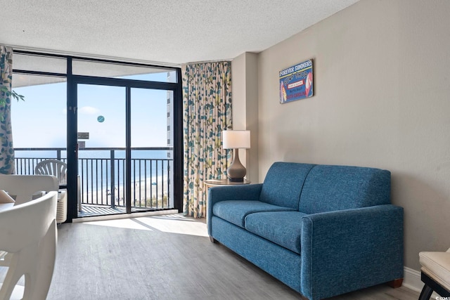 living room featuring hardwood / wood-style flooring, a textured ceiling, expansive windows, and a water view