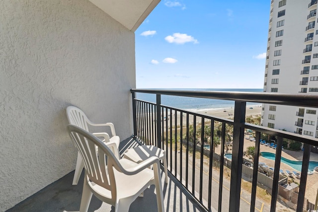 balcony with a water view and a view of the beach