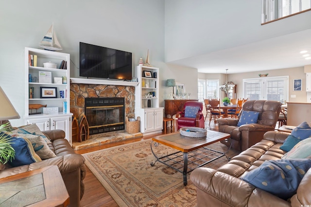 living room with a stone fireplace, an inviting chandelier, and hardwood / wood-style flooring