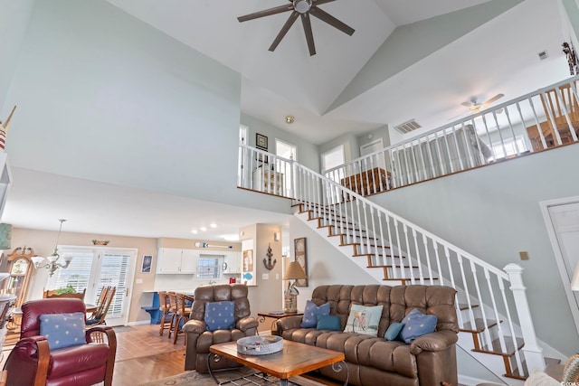 living room featuring ceiling fan with notable chandelier, light hardwood / wood-style flooring, and high vaulted ceiling