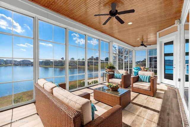 sunroom with plenty of natural light, ceiling fan, wood ceiling, and a water view