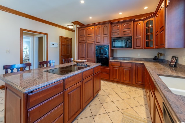 kitchen featuring light tile patterned floors, a kitchen breakfast bar, black appliances, crown molding, and light stone counters