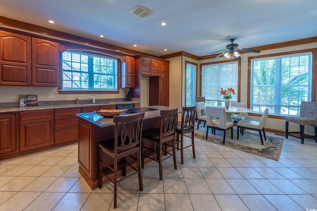 kitchen featuring light tile patterned flooring, ornamental molding, a breakfast bar, and plenty of natural light