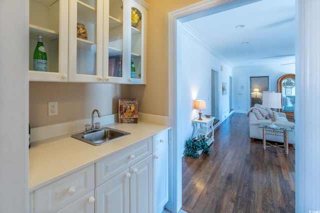 bar featuring dark hardwood / wood-style flooring, ornamental molding, sink, and white cabinets