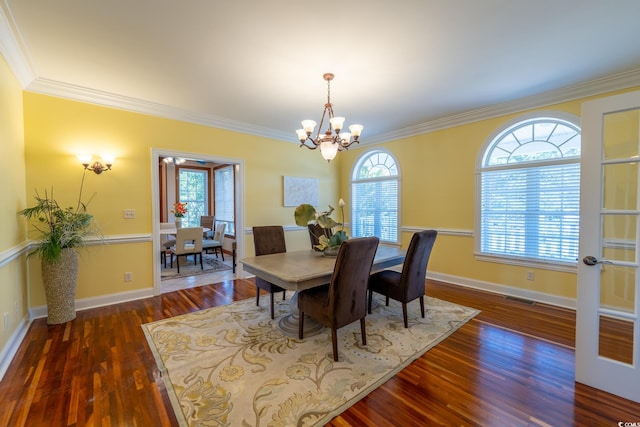 dining space with dark wood-type flooring, crown molding, and a chandelier