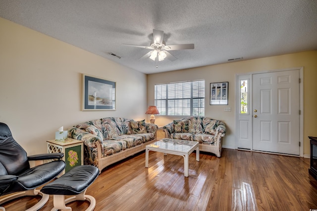 living room with a textured ceiling, hardwood / wood-style flooring, and ceiling fan