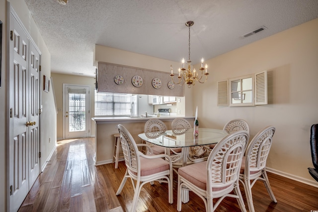 dining room featuring a textured ceiling, a notable chandelier, and wood-type flooring