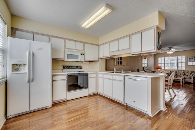 kitchen with white appliances, light wood-type flooring, kitchen peninsula, and white cabinets