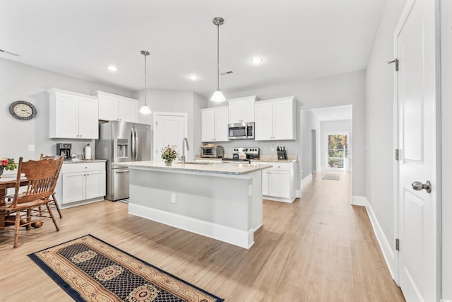 kitchen with a center island with sink, appliances with stainless steel finishes, white cabinets, and light hardwood / wood-style floors