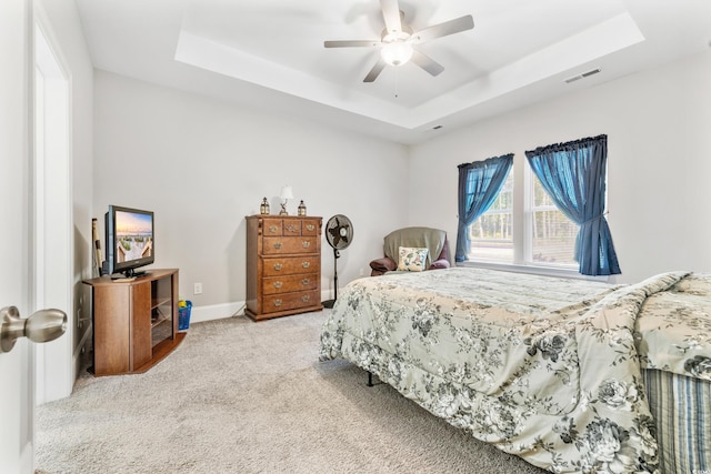 carpeted bedroom featuring ceiling fan and a raised ceiling