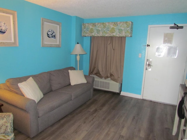 living room with dark hardwood / wood-style floors, a textured ceiling, and radiator heating unit