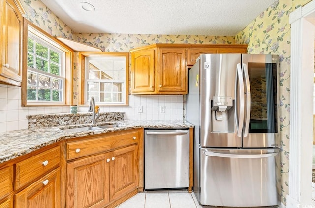 244 George Washington Trl, Georgetown, SC 29440 - kitchen featuring stainless steel appliances, a sink, wallpapered walls, light stone countertops, and a textured ceiling