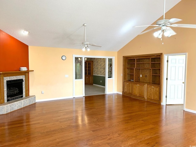 unfurnished living room with a tiled fireplace, ceiling fan, high vaulted ceiling, wood-type flooring, and built in features