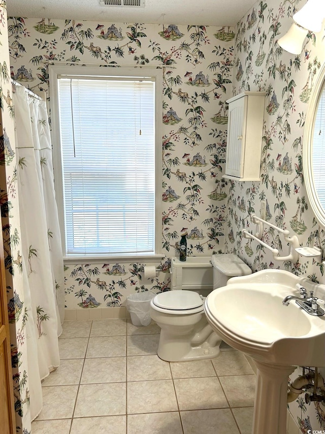 bathroom with a healthy amount of sunlight, tile patterned floors, and toilet