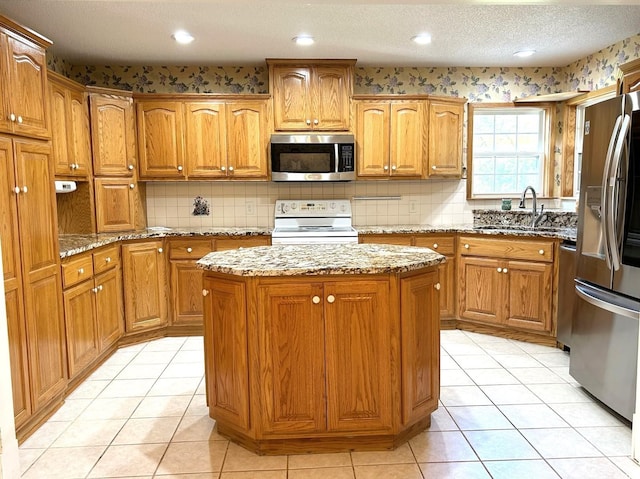 kitchen with sink, a center island, appliances with stainless steel finishes, and light stone counters