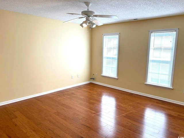 spare room featuring hardwood / wood-style floors, ceiling fan, a textured ceiling, and a wealth of natural light