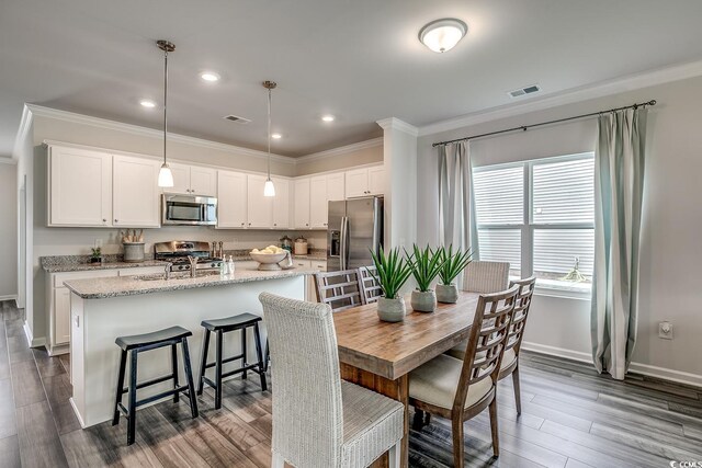 dining area with ornamental molding, hardwood / wood-style flooring, and plenty of natural light