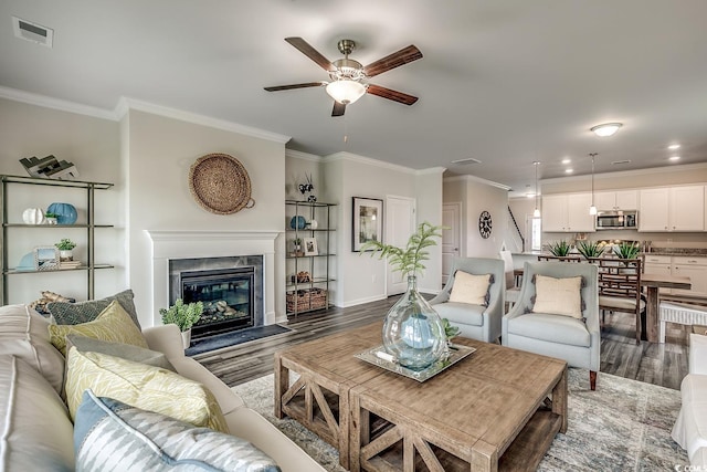 living room with dark wood-type flooring, ornamental molding, and a high end fireplace