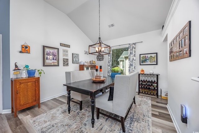 dining room with a chandelier, hardwood / wood-style flooring, and high vaulted ceiling