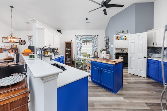 kitchen featuring blue cabinetry, white cabinetry, decorative light fixtures, and light hardwood / wood-style floors