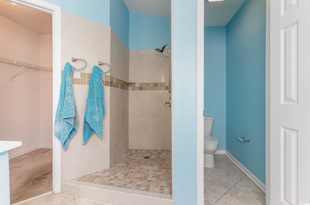 bathroom featuring tile patterned flooring, a tile shower, and toilet