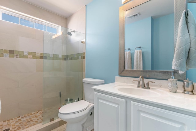 bathroom featuring tiled shower, vanity, and toilet