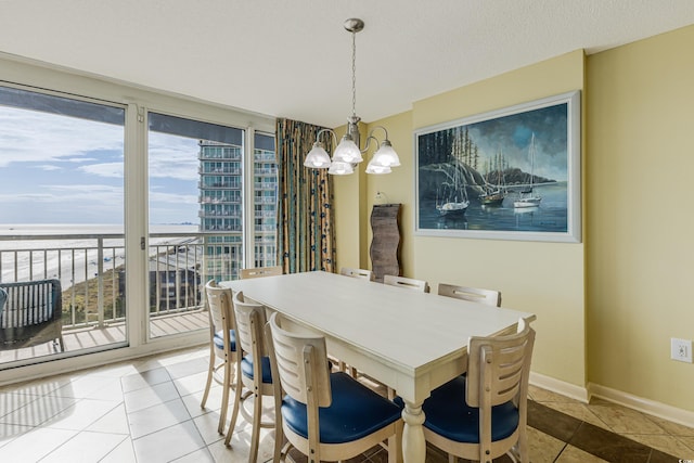 tiled dining space featuring a wealth of natural light, a textured ceiling, a water view, and an inviting chandelier