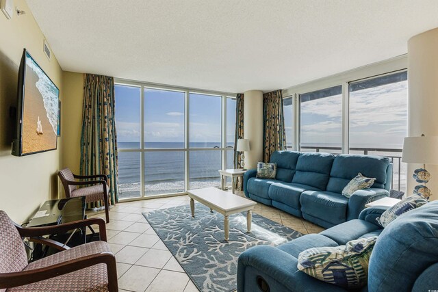 living room featuring a water view, light tile patterned flooring, a textured ceiling, and a wealth of natural light