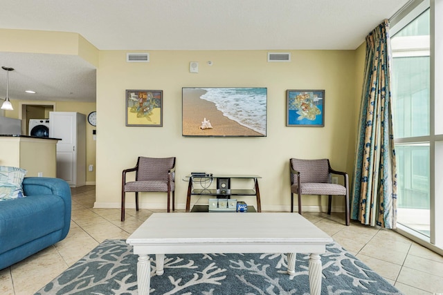 living room with a textured ceiling, washer / clothes dryer, and light tile patterned floors