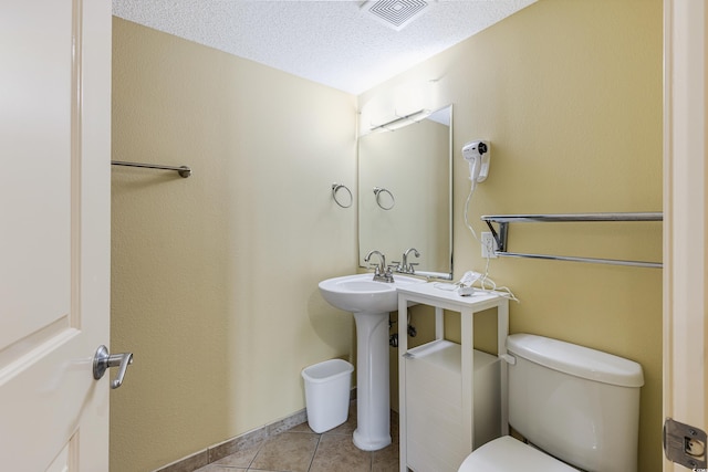 bathroom with toilet, a textured ceiling, and tile patterned floors