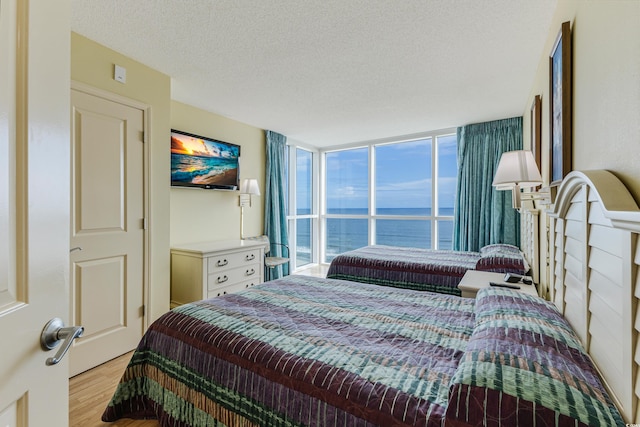 bedroom with a textured ceiling, expansive windows, and light hardwood / wood-style flooring