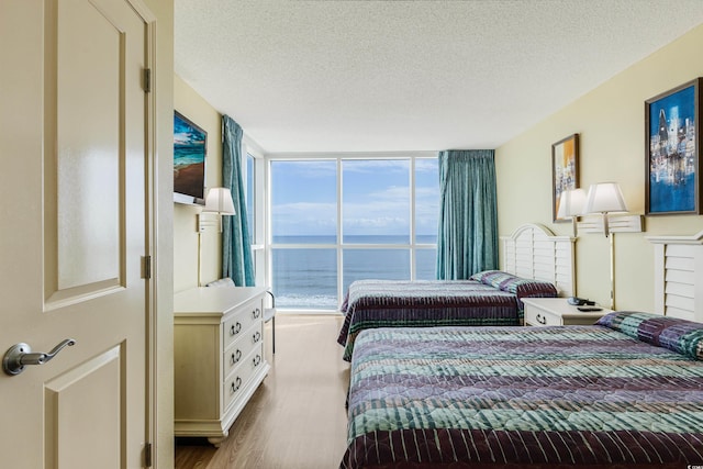 bedroom with light hardwood / wood-style floors, a textured ceiling, and floor to ceiling windows